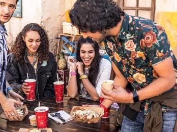 Disney's Animal Kingdom Theme Park A group of 4 teenagers sat at a table eating food and drinking soft drinks from red cups