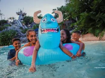 Disney H2O Glow After Hours at Typhoon Lagoon Four children in a lazy river with a pool float designed to look like Sully from Monsters Inc