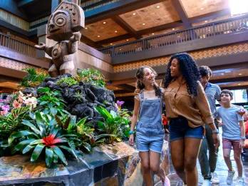 A woman and girl walking through a Polynesian inspired hotel lobby