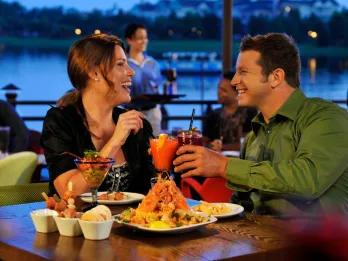 Disney Springs A couple eating and drinking cocktails at a table in a lakeside restaurant