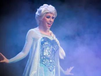 Frozen Singalong Celebration Elsa from Frozen standing on a stage with her arms out singing Let It Go