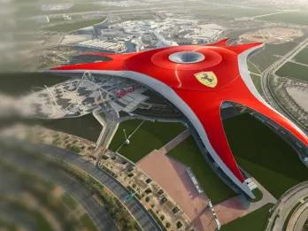 A large red building shaped in a triangle with a large yellow badge on it with a black horse on top which is the Ferrari badge. There are roads and rollercoasters coming out of this large building.