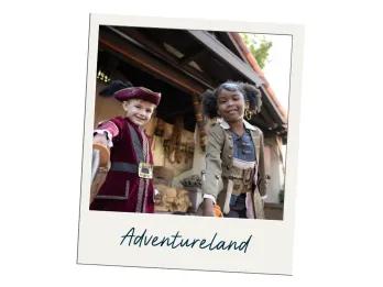 Adventureland Image of two young kids in pirate costumes with the label "Adventureland" on the polaroid frame. The boy is holding a toy sword up towards the camera in a red coat and pirate hat. The girl is wearing a brown coast with a black eye patch on her forehead. She is also holding a toy sword off camera.