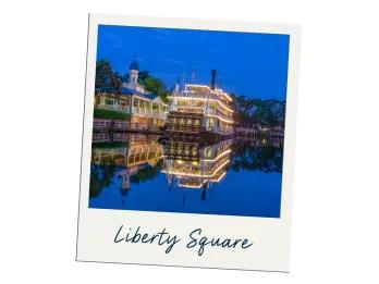 Liberty Square There is a large lake with some trees lining it. Docked up there is a large 3 storey steam boat called the "Liberty Belle" lined with yellow lights.