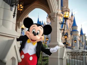 Magic Kingdom Park Mickey Mouse standing in front of Cinderella Castle with his arm outstretched