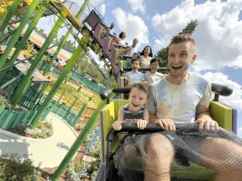 Trolls Trollercoaster in DreamWorks Land A father and son riding at the front of a rollercoaster
