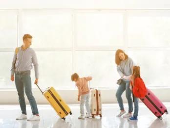 A family walking through a train station with suitcases