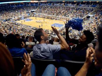 Orlando Magic Basketball Two friends high-fiving while watching an Orlando Magic game