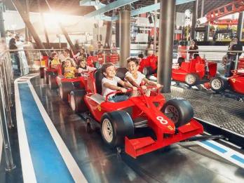 Ferrari World, Yas Island Small kids sat on rollercoaster car which is shaped like a red Ferrari Formula 1 car