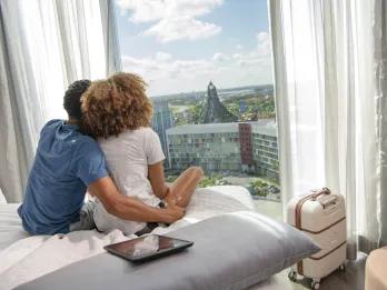 Universal Orlando Resort hotels A couple sat on a hotel bed looking out the window to Volcano Bay