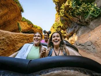 Zwei junge Frauen halten sich an den Händen und lächeln während Sie auf einer Wasserrutsche sind, kurz vor der Abfahrt steht.