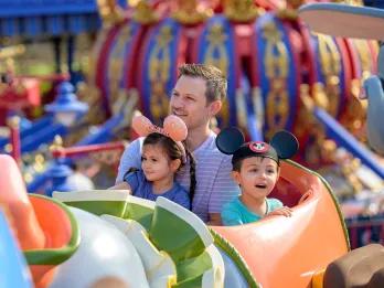 Dumbo the Flying Elephant Two children and their father sat in a ride vehicle shaped like Dumbo