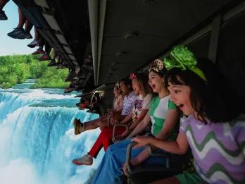 Soarin' Around the World A row of people on a ride vehicle hanging a screen showing a waterfall