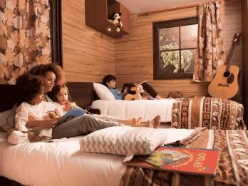 Disney Davy Crockett Ranch at Disneyland Paris A family relaxing and reading on beds in a wooden cabin at Davy Crockett Ranch
