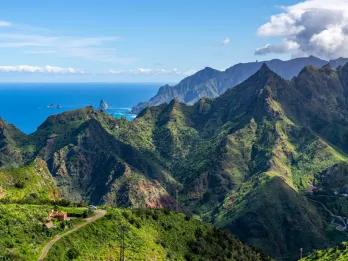 Grüne Bergkette auf Teneriffa mit blauem Meer und Himmel im Hintergrund