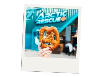 SeaWorld All-Day Dining A polaroid image of a hand holding a pretzel above the Arctic Rescue ride sign at SeaWorld