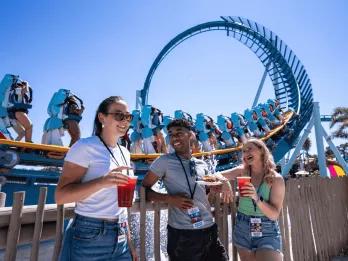 Seven Seas Food Festival at SeaWorld Orlando Three young adults stood in front of the Pipeline rollercoaster drinking cocktails and eating festival plates