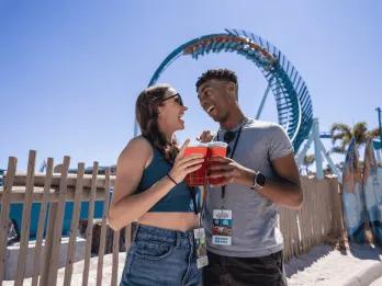 SeaWorld Seven Seas Food Festival A couple posing with drinks in front of the Pipeline rollercoaster at SeaWorld