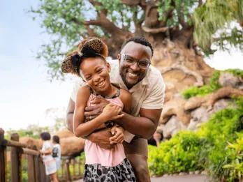 A man and young girl hugging in front of the Tree of Life