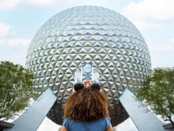 A young girl standing facing Spaceship Earth