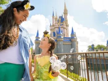 Magic Kingdom Park A mom and daughter in a princess dress walking in front of Cinderella Castle