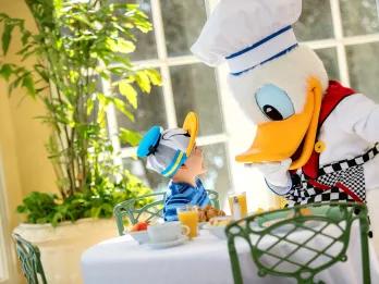 Disney Dining Plan A young boy wearing a Donald Duck hat meeting Donald Duck in a chef outfit