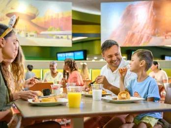 Grey table full of breakfast plates with Mickey waffles and glasses of orange juice.