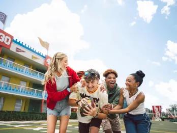 A group of friends playing with an American football in front of a motel-style building