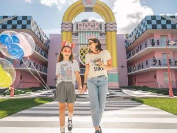 A woman and girl walking away from a large jukebox holding balloons and laughing