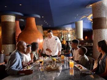 A chef meeting with a family sat at a table in a restaurant