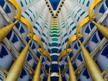 Gold pillars holding up the grand multi-coloured structure which has different colour for each floor. The inside is open in a triangle shape.