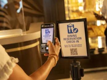 Mobile check-in Poster with checkboard and a knife and fork cartoon icon and check mark. It says dining reservation check in and someone is holding their phone up to scan a QR code.