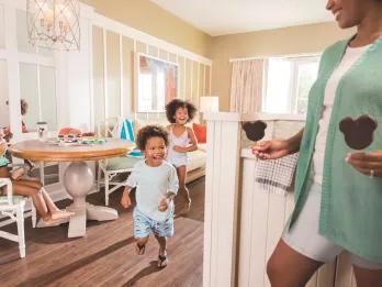 A young boy running towards a man holding out two ice creams in the shape of Mickey Mouse