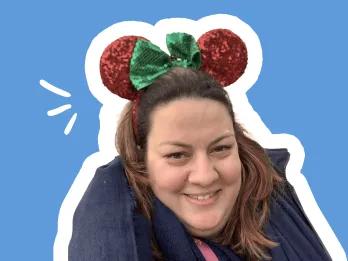 smiling female with long brown hair and mickey mouse ears, on blue background