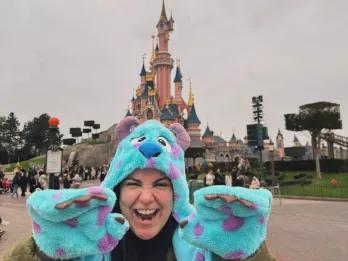 Camila Female with Monsters Inc hat and gloves stood in front of Disney castle