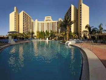 An empty swimming pool in front of a hotel tower block