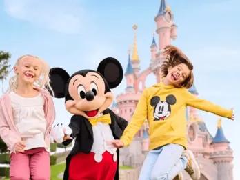 Kinder in Disneyland Paris Zwei junge Mädchen springen mit Micky vor dem Schloss von Disneyland Paris