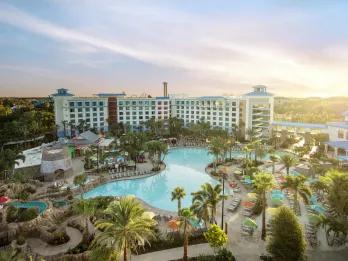 Loews Sapphire Falls Resort A large hotel with a magnificent giant pool with lots of palm trees around it. There are also deck chairs surrounding it.