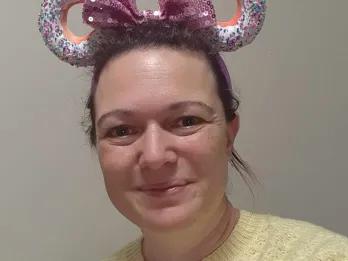 Mandy Smiling female in yellow top wearing pink sparkly Disney ears