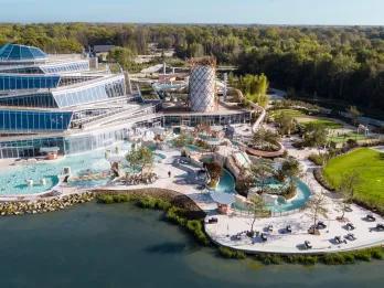 Les Villages Nature Paris Huge water complex outside of a modern hotel building. There's a regular pool, long winding lazy river and other fun water activities.