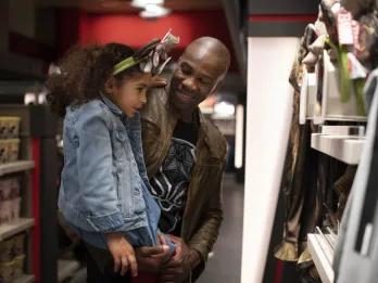 Disney Hotel New York – The Art of Marvel Man holding his daughter in resort shop which has red superhero theming.