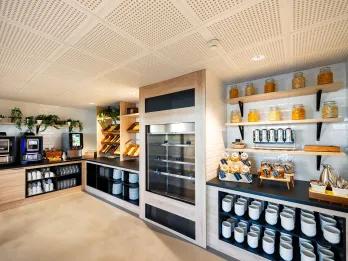 Modern sleek kitchen design with plates stacked and multiple pastries and drinks laid out for guests