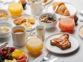 Ki Space Hotel & Spa White table cloth set table with fruit plates, juices, cups of tea, toast with jam o it, croissants and many more delicious foods.