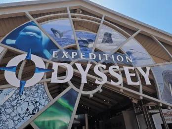 Circular sign which says "Expedition Odyssey" with images of different animals in the background including a beluga whale, humpback whale and more!