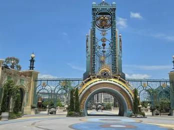 Grand entrance with a semicircle portal opening and above there's a statue of a planet and star constellation.