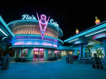 Retro diner themed restaurant lit up at night in neon green and pink lights.