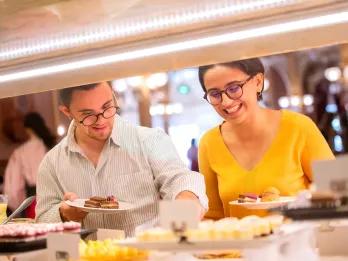 Two people choosing desserts from a buffet