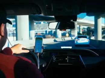 Man driving car on a highway following a navigation system on his phone.