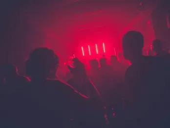 People clubbing in dark room with red neon lights. 