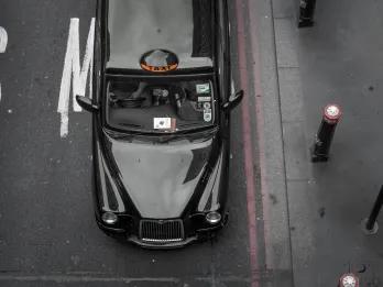 Black cab driving down road.
